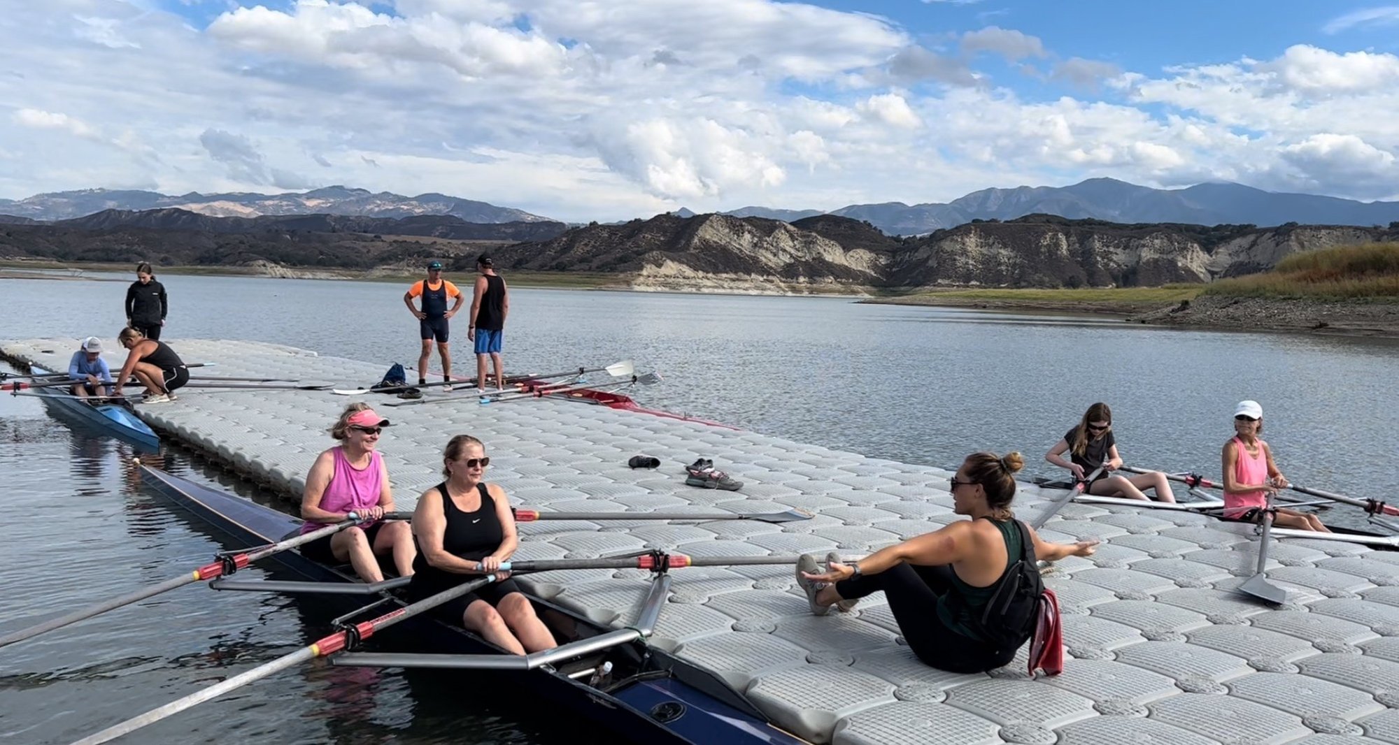 group learn to row, rowers sitting on a dock listening to coach